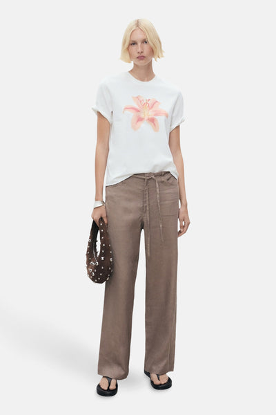 Wit T-shirt met korte mouwen en bloemenprint, van MANGO, gedragen met een lichtbruine broek en zwarte sandalen.