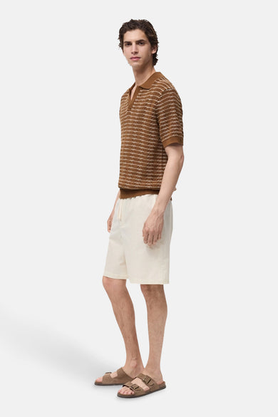 Bruin poloshirt met korte mouwen van MANGO met een horizontaal strepenpatroon, gedragen met een beige short.