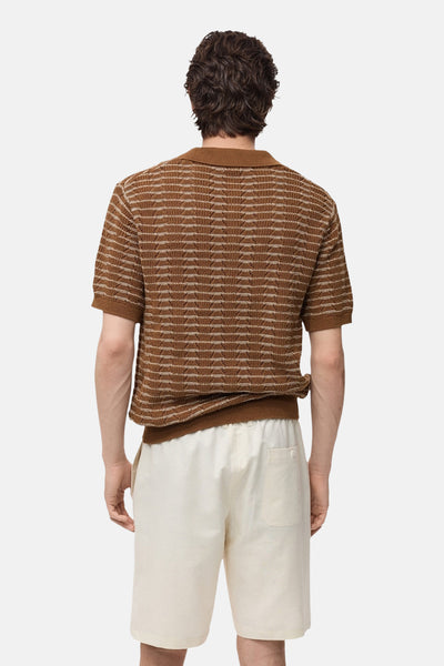 Polo à manches courtes marron de MANGO, à rayures horizontales avec texture tricotée, porté avec un short beige.
