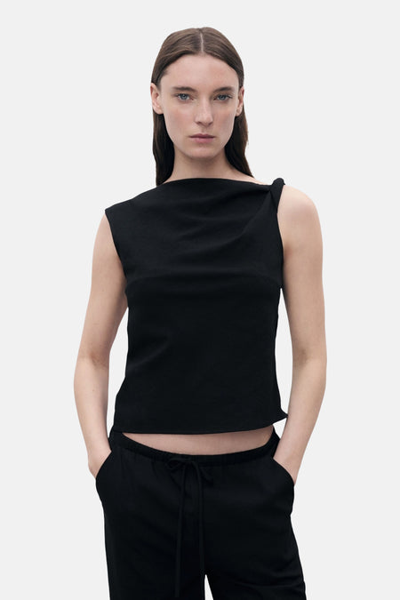 Zwart hemdje van MANGO, met een effen achterkant en gedragen met een bijpassende zwarte broek.