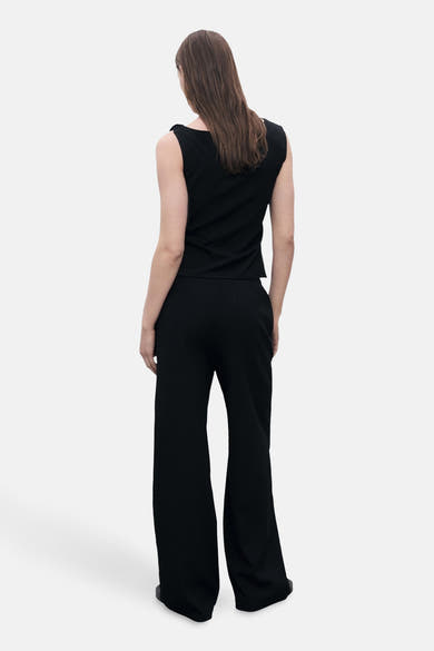 Débardeur noir by MANGO, avec un dos uni et porté avec un pantalon noir assorti.