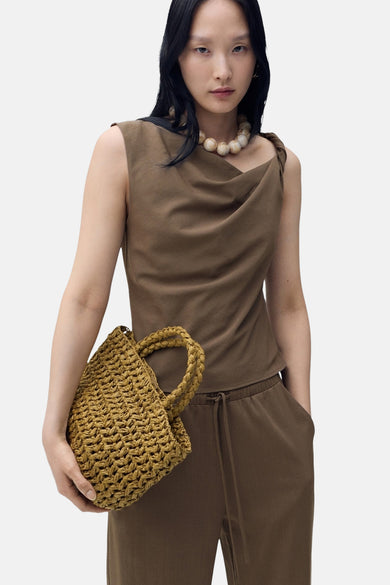 Bruin hemdje van MANGO, met gedrapeerde halslijn en gedragen met een parelketting en een gevlochten tas.
