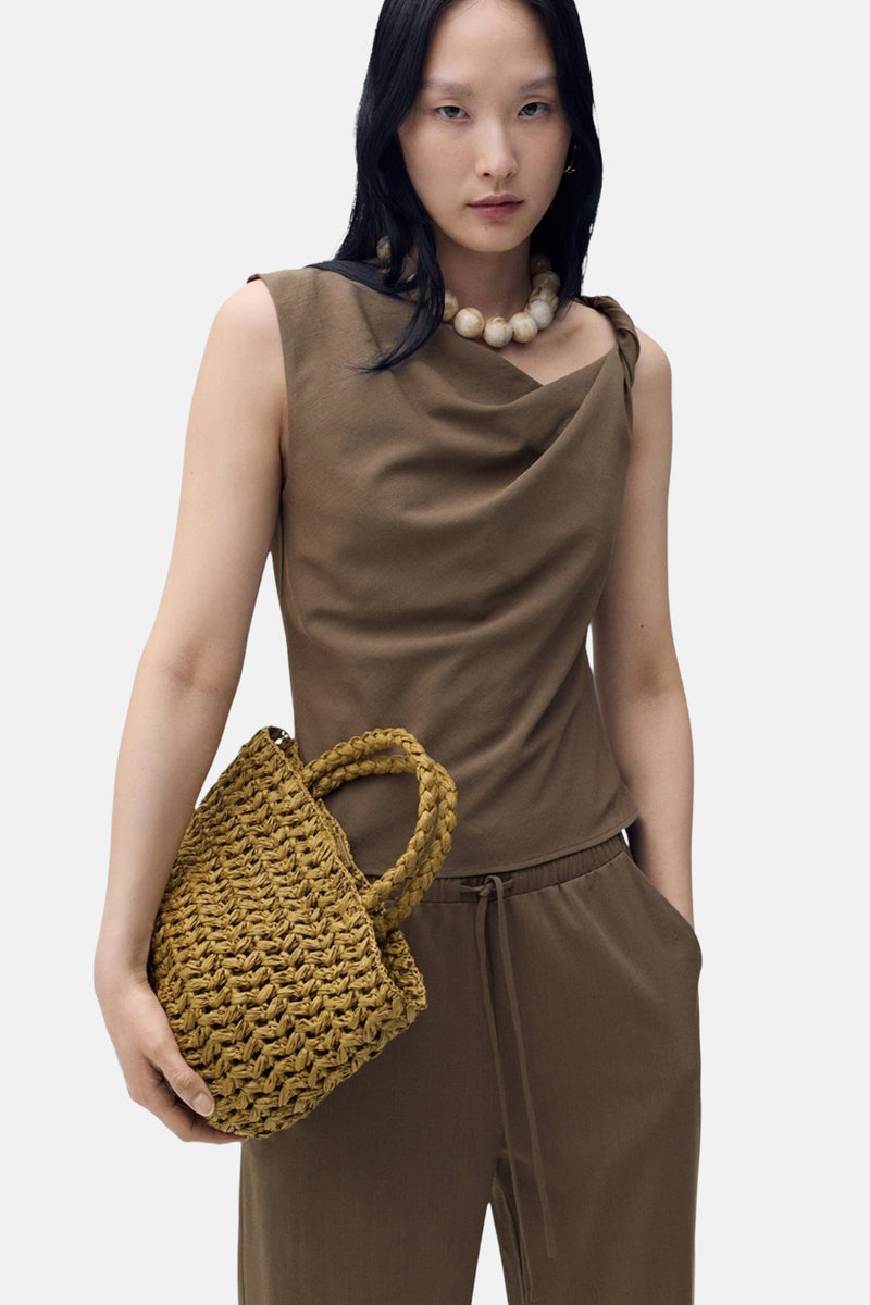Bruin hemdje van MANGO, met gedrapeerde halslijn en gedragen met een parelketting en een gevlochten tas.