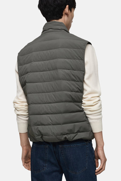Veste sans manches grise de MANGO, portée sur un pull crème et un jean bleu foncé, vue de dos.
