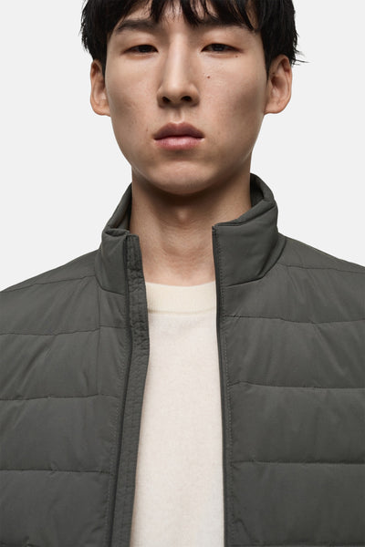 Veste sans manches grise par MANGO, portée avec un pull crème à col rond.