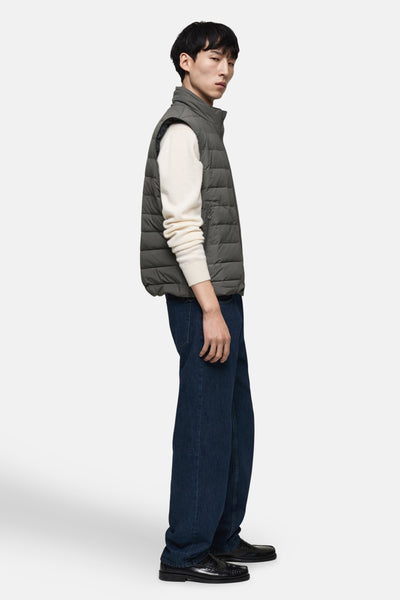 Veste sans manches grise de MANGO, portée sur un pull en maille blanc, avec un jean bleu marine ample.