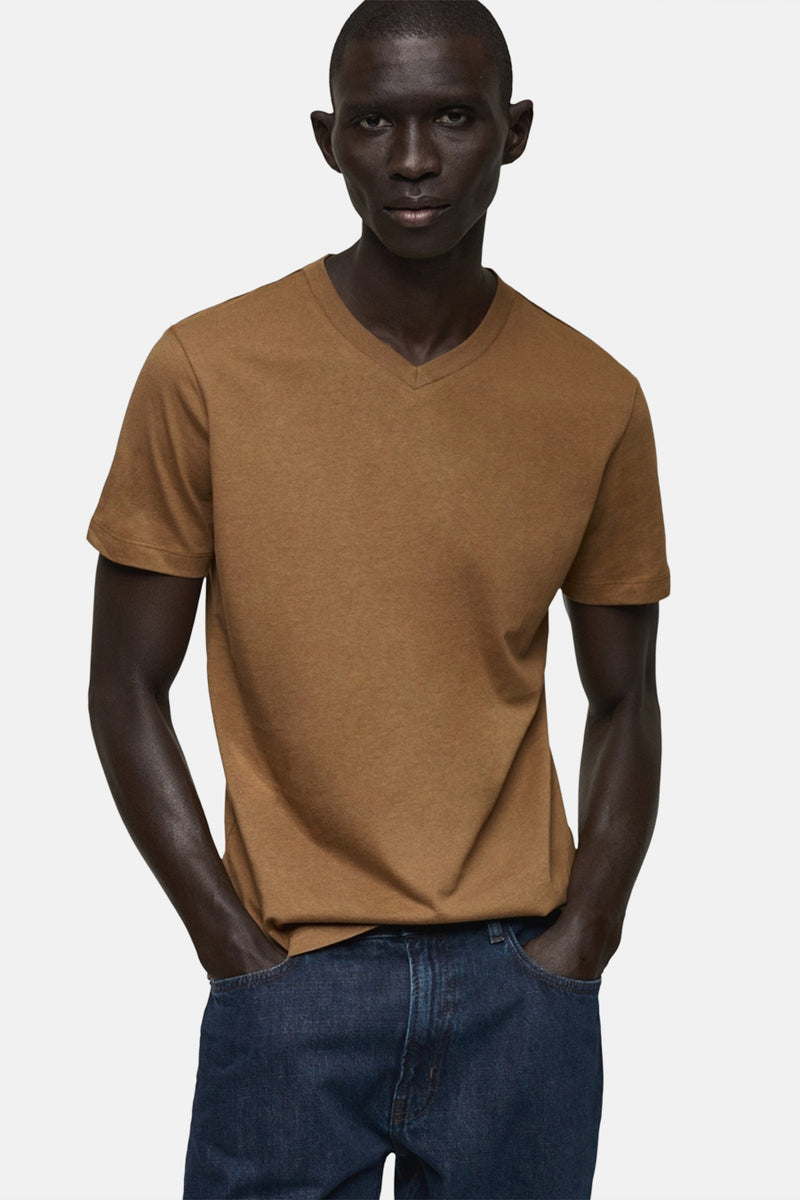 Bruin T-shirt met korte mouwen van MANGO, gedragen met een spijkerbroek, handen in de zakken.