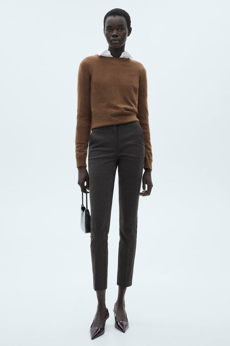 Grijze broek van MANGO, sigarettenmodel, gedragen met een bruine trui en krokodillenleren pumps.