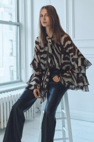Chemisier à manches longues brun de MANGO, motif zébré, porté avec un pantalon en cuir noir.