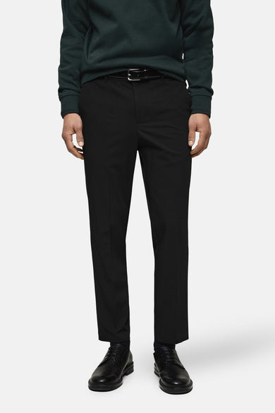 Pantalon de costume noir de MANGO, porté avec un pull vert foncé et une ceinture noire.