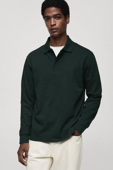 Groen poloshirt met lange mouwen van MANGO, gedragen met een wit T-shirt en een crèmekleurige broek.