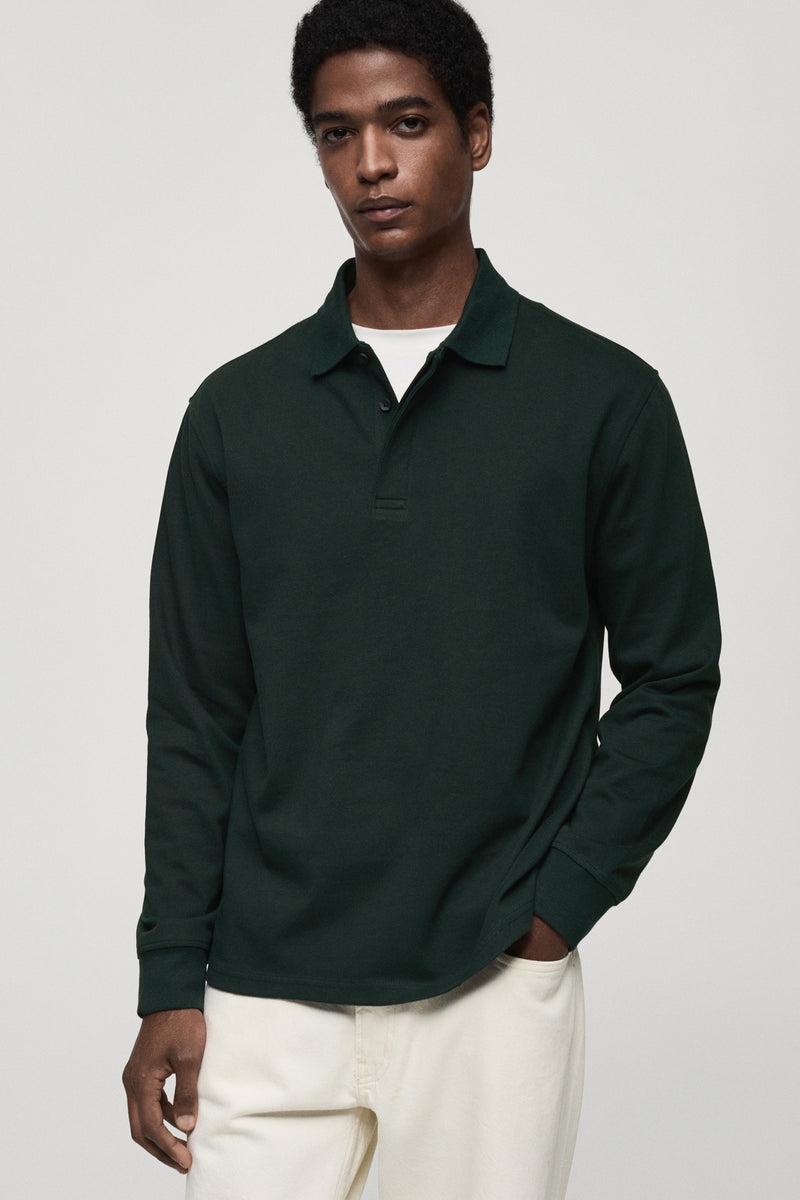 Groen poloshirt met lange mouwen van MANGO, gedragen met een wit T-shirt en een crèmekleurige broek.