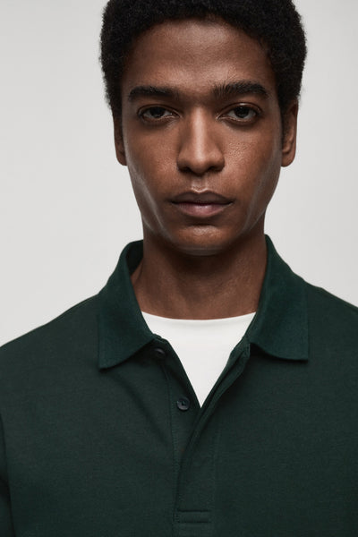 Groene MANGO trui, gedragen over een wit T-shirt, met een gladde textuur en een polokraag.