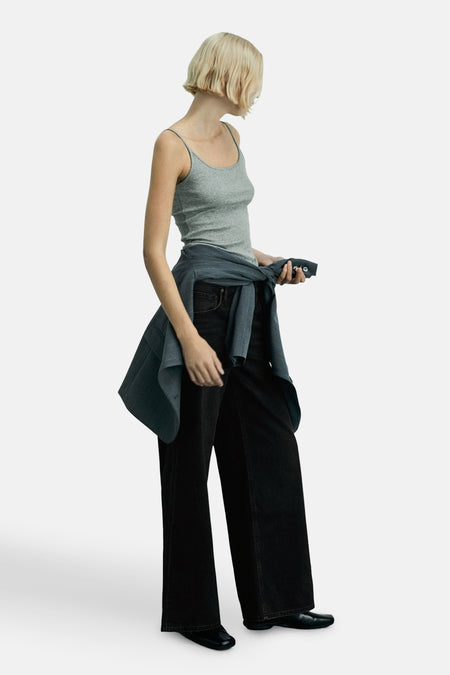 Jean black van MANGO, gedragen met een grijs t-shirt en een shirt dat om de taille is gebonden.