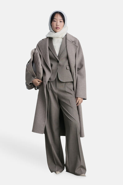 Bruine blazer van MANGO, gedragen met een bijpassende lange jas, wijde broek en een crèmekleurige sjaal.