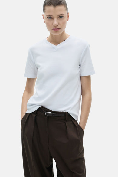 Witte t-shirt met korte mouwen van MANGO, gedragen met een hoge taille donkere broek, rugweergave.