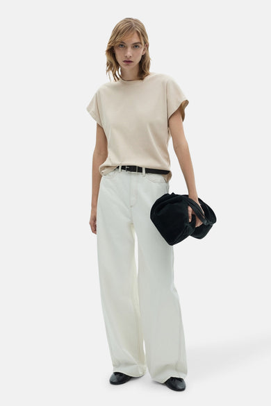 Beige t-shirt met korte mouwen van MANGO, gedragen met een witte broek, een zwarte riem en zwarte ballerines.