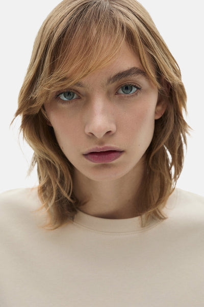 T-shirt beige à manches courtes de MANGO, porté par un mannequin aux yeux bleus et aux cheveux blonds.