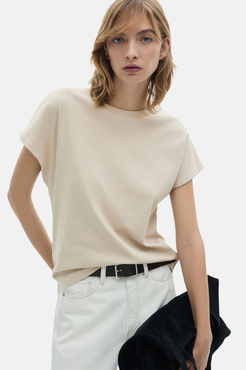 Beige t-shirt met korte mouwen van MANGO, gedragen met een witte broek en een zwarte riem.