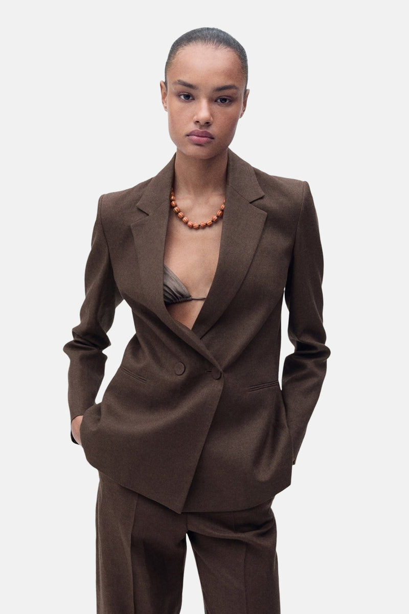 Blazer brun par MANGO, porté ouvert avec un haut de bikini et un collier orange.