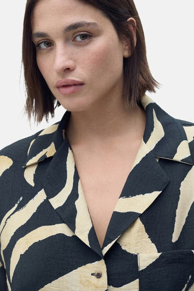 Chemise noire à manches courtes de MANGO, imprimé zébré beige, coupe décontractée et col tailleur.
