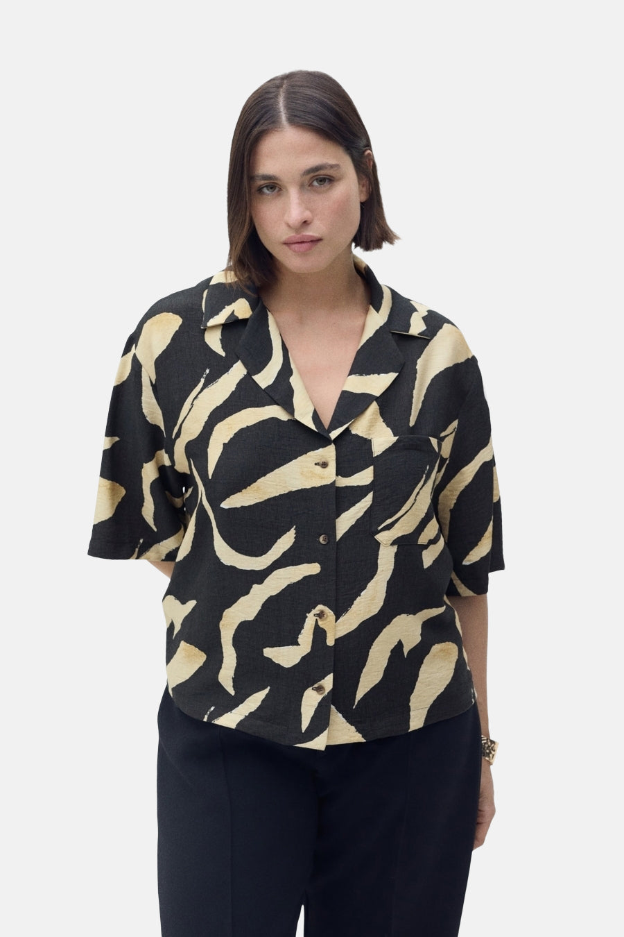 Chemise à manches courtes noire par MANGO, à motifs abstraits crème, avec poche poitrine.
