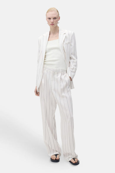 Witte tanktop van MANGO, gedragen met een gestreept pak en zwarte sandalen.