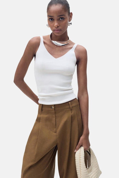 Débardeur blanc de MANGO, porté avec un pantalon marron taille haute et des accessoires argentés.