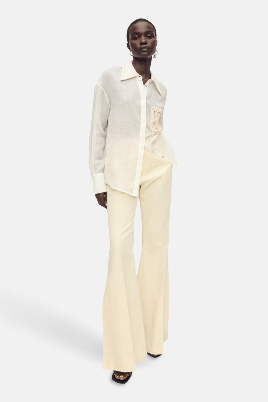 Witte blouse met lange mouwen van MANGO, met gehaakte zak en crèmekleurige uitlopende broek.