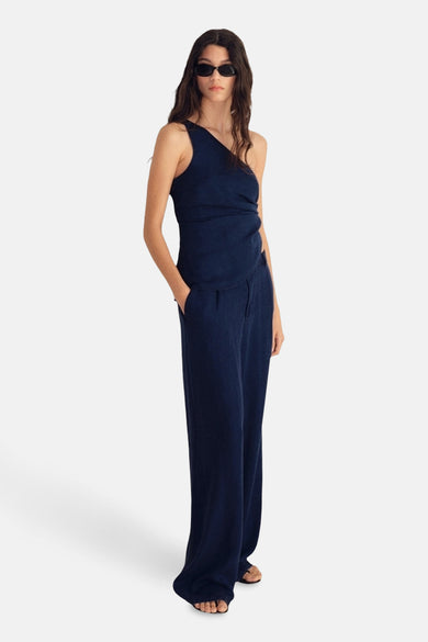 Donkerblauwe spijkerbroek van MANGO, losse pasvorm en wijde pijpen, gedragen met een asymmetrische top en een zonnebril.