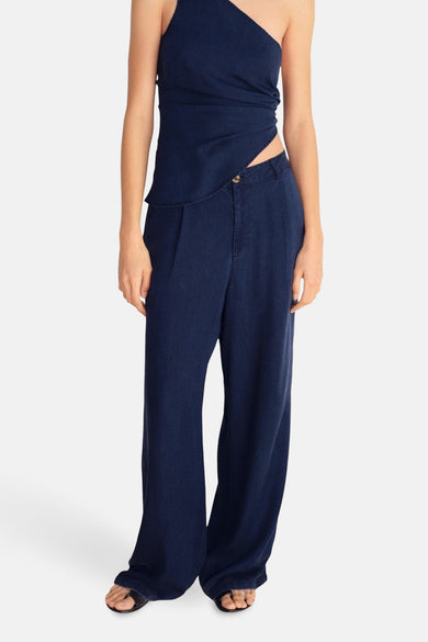 Donkerblauwe spijkerbroek van MANGO, wijde pasvorm met plooien, gedragen met een asymmetrische top.