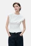 Wit mouwloos topje van MANGO, met geplooide taille en gedragen met een donkerblauwe jeans.