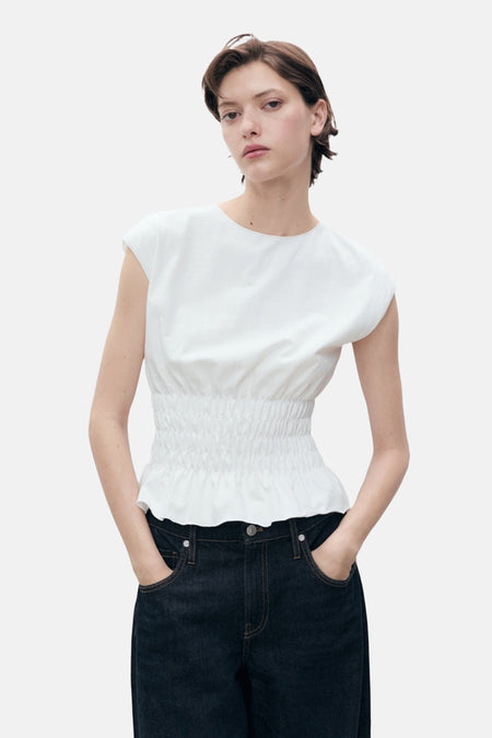 Wit mouwloos topje van MANGO, met geplooide taille en gedragen met een donkerblauwe jeans.