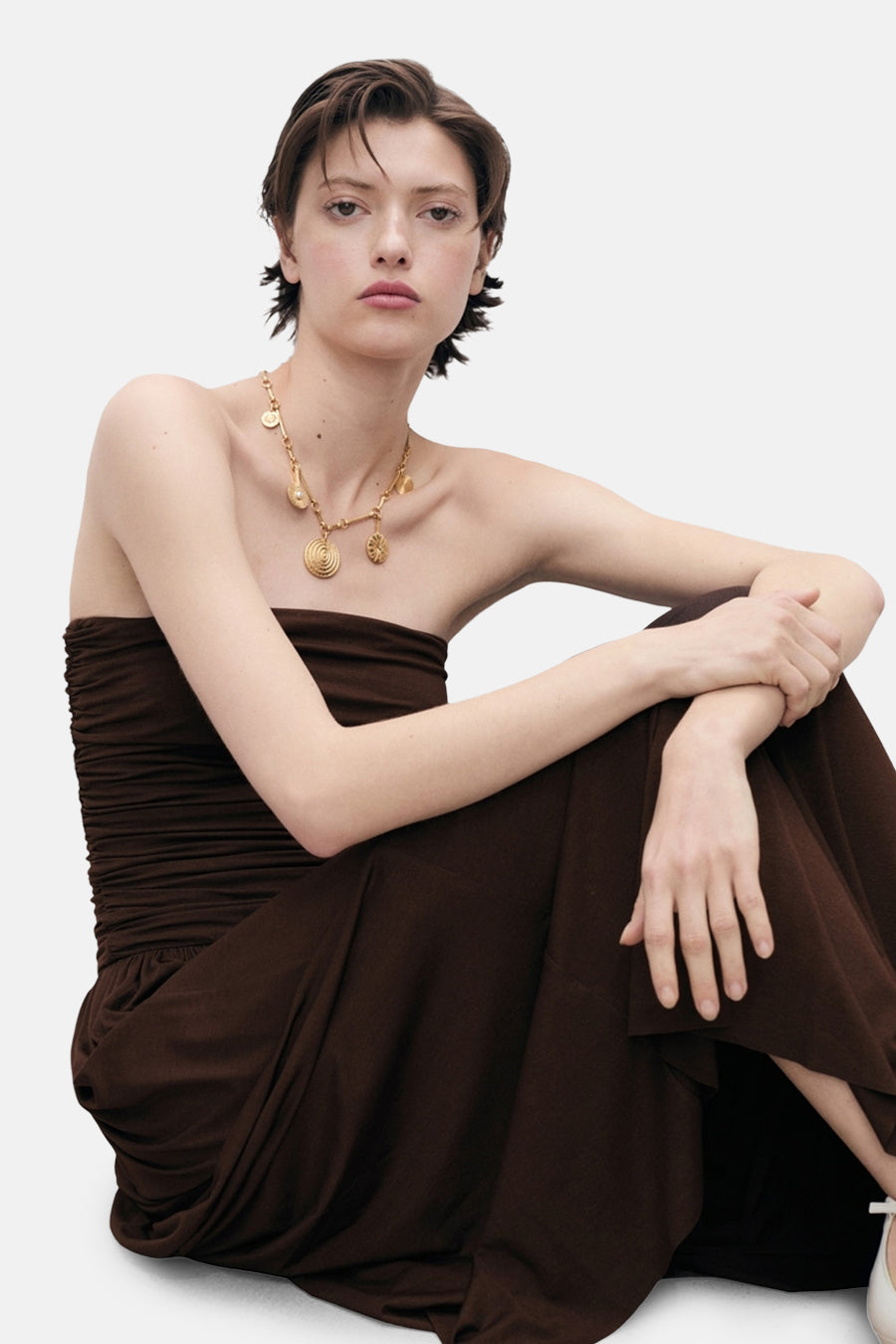 Bruine jurk van MANGO gedragen door een model, met een gouden ketting met bedeltjes.