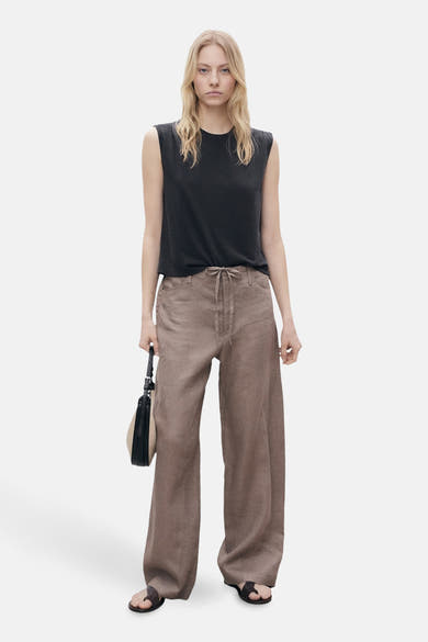 Zwarte mouwloze top van MANGO, gedragen met een bruine wijde broek met trekkoord.