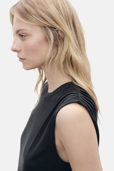 Zwart mouwloos topje van MANGO, geplooid detail op de schouder, gedragen door een blond model.