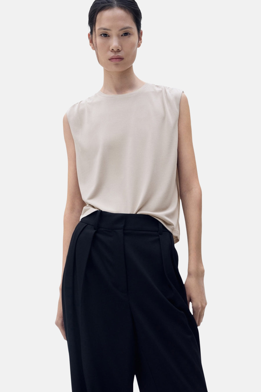 Beige mouwloze top van MANGO, met een effen achterkant en gedragen met een zwarte broek.