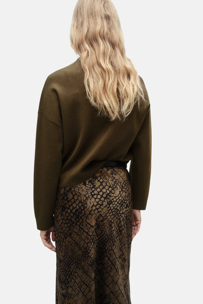 MANGO kaki-pullover, gedragen met een harenpatroon jupe en een zwarte riem.