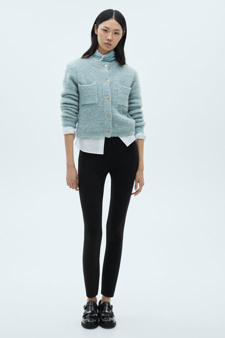 Blauwe MANGO bodywarmer met gouden knopenzakken gedragen over een witte blouse en een zwarte broek.