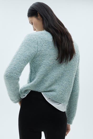 Blauwe MANGO bodywarmer, bouclé textuur, gedragen met een zwarte broek en een wit T-shirt.