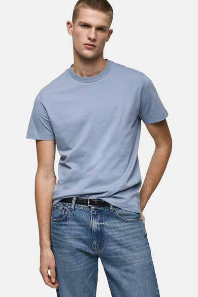 T-shirt bleu à manches courtes de MANGO, porté avec un jean et une ceinture noire.
