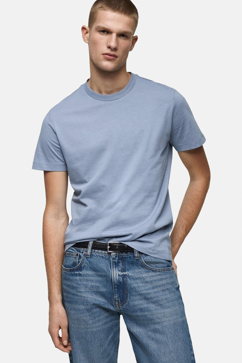 T-shirt bleu à manches courtes de MANGO, porté avec un jean et une ceinture noire.
