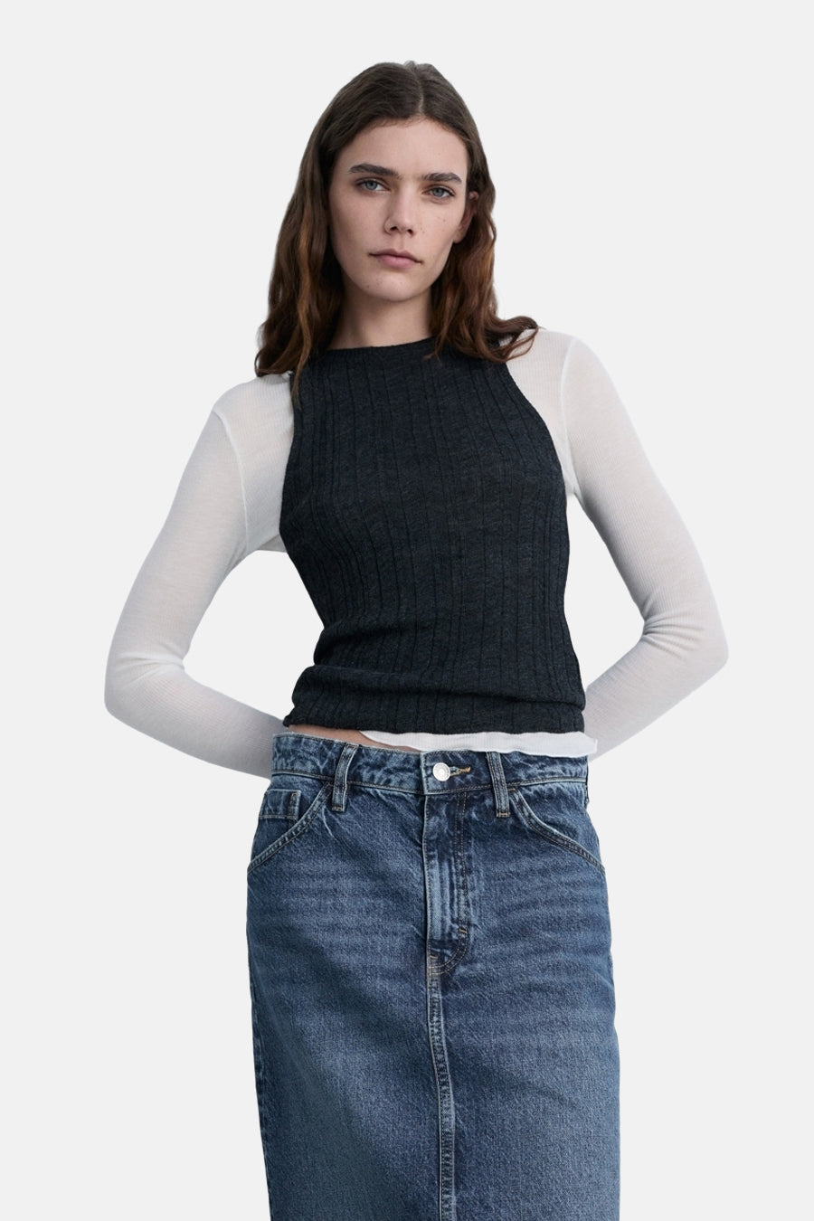 Jupe midi en denim bleu moyen de MANGO, portée avec un haut à manches longues blanc et gris.
