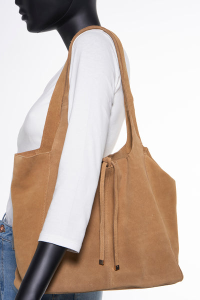 Bruine suède handtas van MANGO, schoudertas, met trekkoorden en een paspop met een wit T-shirt en een spijkerbroek.
