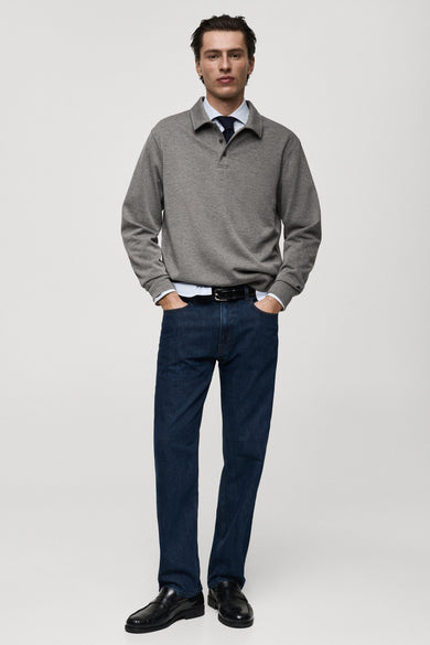 Grijze polo-sweater van MANGO, gedragen over een overhemd met een stropdas, met een spijkerbroek en loafers.