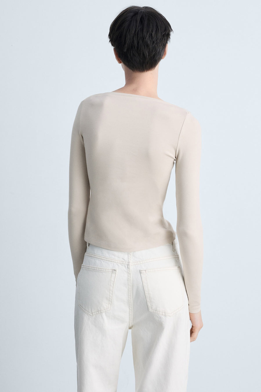 T-shirt beige à manches longues de MANGO, porté avec un jean blanc taille haute, vue de dos.
