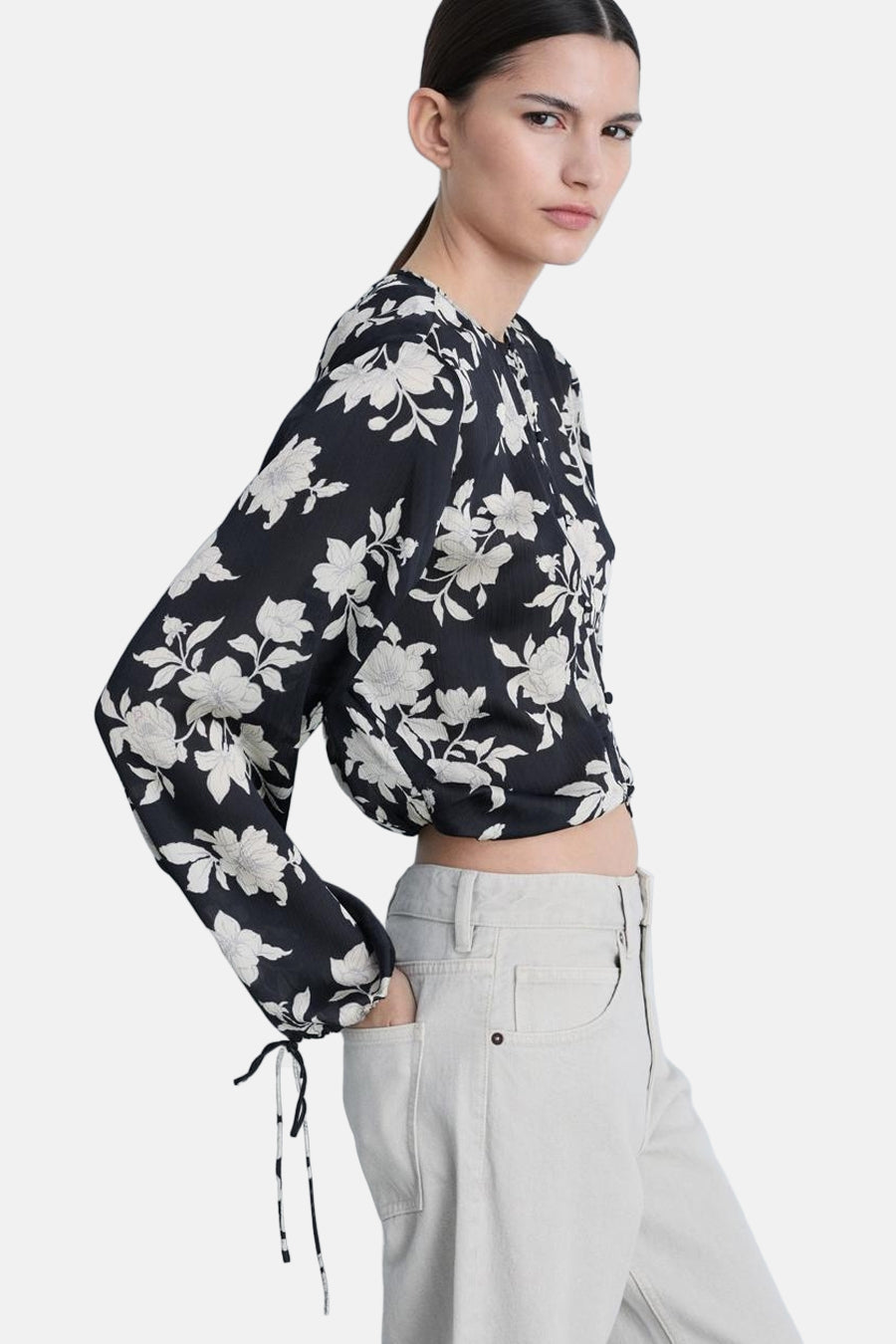 Blouse met lange mouwen met veelkleurig bloemenpatroon van MANGO, achterkant, gedragen met een lichte, wijde jeans.