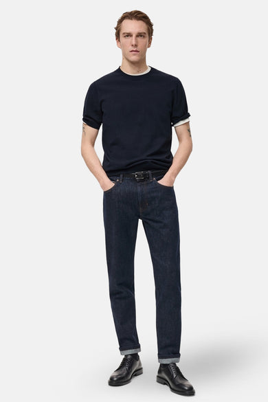 T-shirt à manches courtes bleu foncé de MANGO, porté avec un jean brut, ceinture noire et chaussures en cuir.