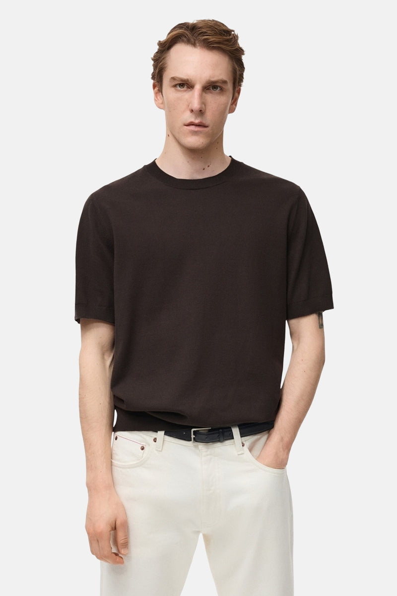T-shirt à manches courtes brun de MANGO, porté avec un pantalon blanc et une ceinture noire.