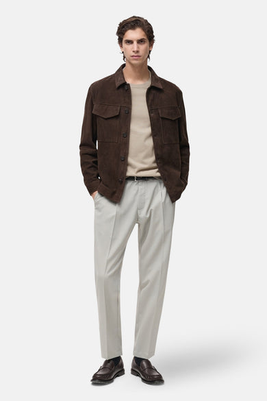 T-shirt beige à manches courtes de MANGO, porté avec une veste en daim marron et un pantalon clair.
